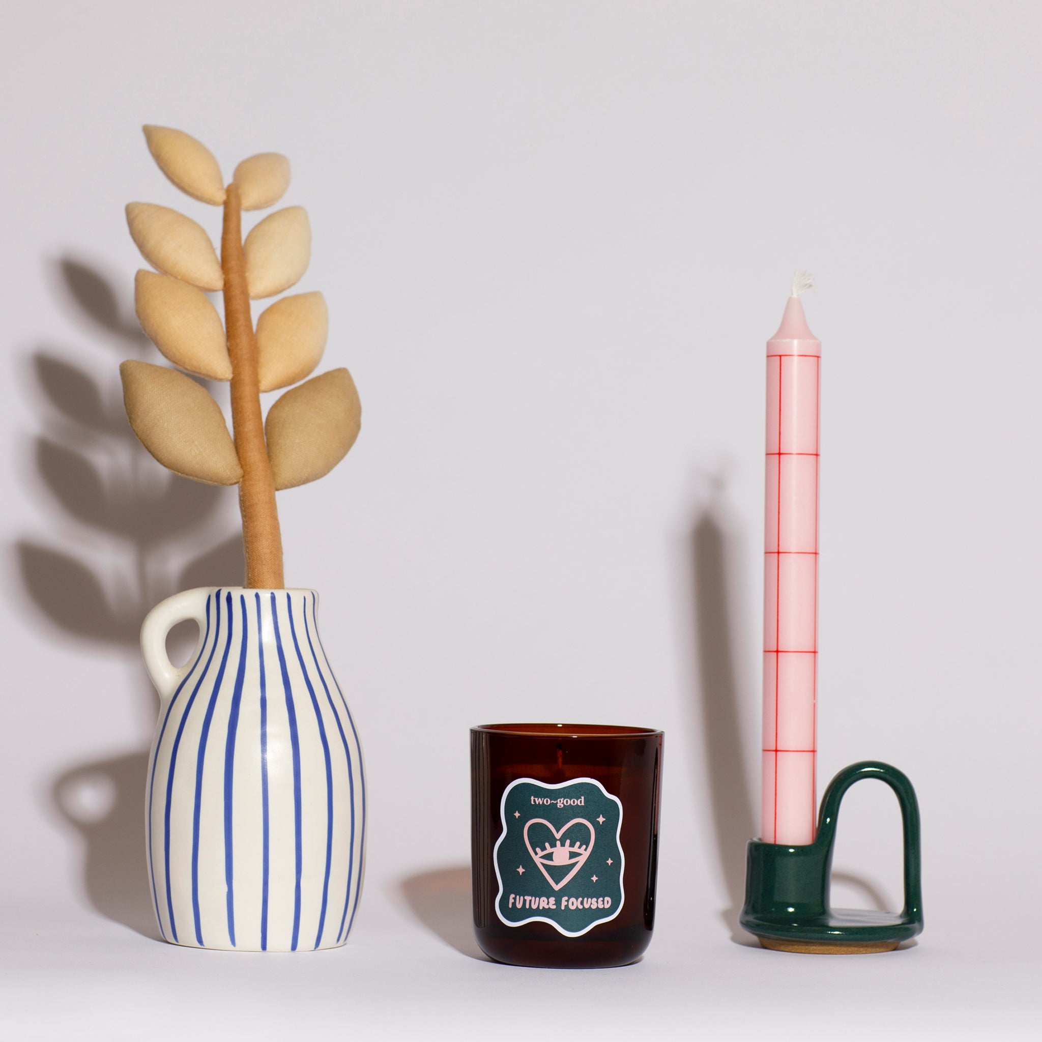 Decorative items including a vase with leaves, a candle, and a small candle holder on a light grey background. House scene