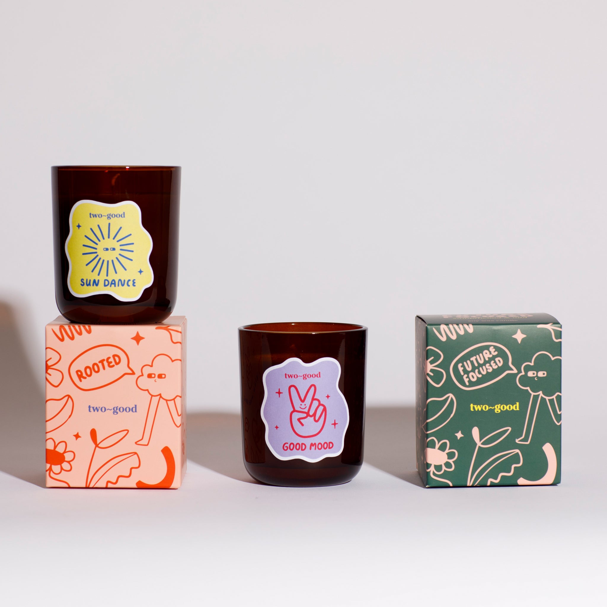 Two candles with decorative labels and packaging on a white background bold illustrations on boxes