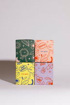 Four colourful candle boxes with illustrations and linear designs on a grey background